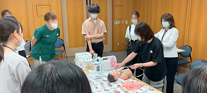 公立豊岡病院組合立豊岡病院にてJANAを用いた実習の様子と看護学生がJANAを抱っこするイラスト